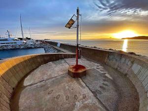 a street light next to the water with a sunset at Rokkaria Holidays Apartments in Villasimius