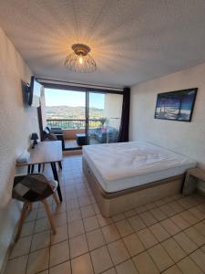 a bedroom with a bed and a table and a window at Les Terrasses in Bormes-les-Mimosas