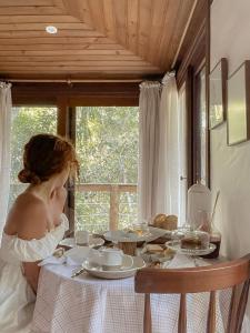 a woman sitting at a table with food on it at Aurora e Vale in Praia do Rosa