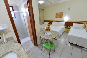 a hotel room with two beds and a table with flowers on it at Vind's Plaza Hotel in Caratinga