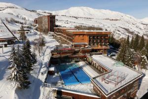 a building with a swimming pool in the snow at Appartements Immeuble Zodiaque in Le Corbier