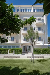 a white building with a tree in front of it at Hotel Riviera in Milano Marittima