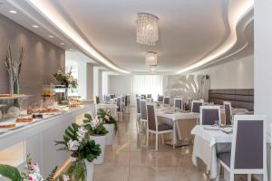 a restaurant with white tables and chairs and a buffet at Hotel Riviera in Milano Marittima