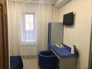 キスロヴォツクにあるKorona Hotelの青い椅子、デスク、電話が備わる客室です。