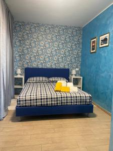 a blue bedroom with a bed with two yellow pillows at E&C Suites Roma in Lido di Ostia
