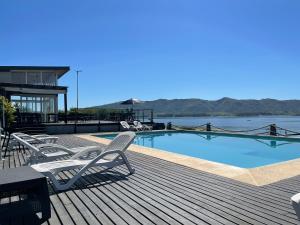 a deck with chairs and a swimming pool next to the water at Casa Puerto del Aguila - Potrero de Garay in Potrero de Garay