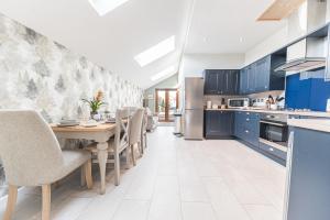 a kitchen with blue cabinets and a table and chairs at The Black Dog Cottage in Dalton in Furness