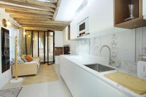 una cucina bianca con lavandino e divano di Apartment Le Marais by Studio prestige a Parigi