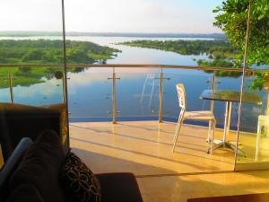 einen Glasbalkon mit einem Tisch, Stühlen und Wasser in der Unterkunft Boulevard 251 Riverside Apartments in Iquitos