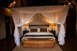 1 dormitorio con 1 cama con dosel y 2 lámparas en Nungubane Game Lodge, en Reserva de Welgevonden