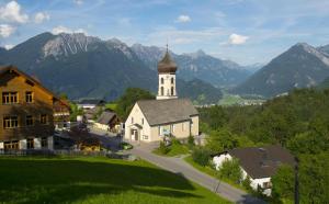 a church on a hill with mountains in the background at Apartment Boden in Bürserberg