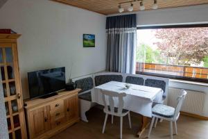 uma sala de jantar com uma mesa e cadeiras brancas e uma televisão em Gästehaus Alpensicht em Grafenhausen