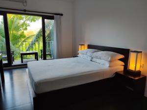 a bedroom with a bed with two lamps and a window at Lakmini Lodge Sigiriya in Sigiriya