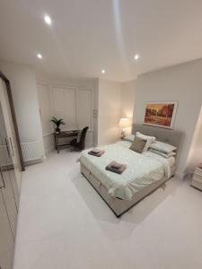 a white bedroom with a large bed and a desk at Explore East Devon from here.. in Exmouth
