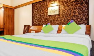 a bedroom with a bed with white sheets and colorful pillows at Treebo Sahara Shivaji Nagar in Pune +30 photos