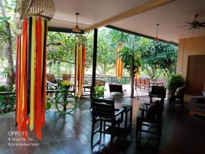 una camera con tavolo, sedie e tende arancioni di Farm Madame Fleur a Petchaburi