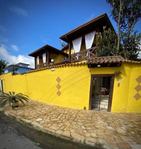 a yellow house with a yellow wall at MAI Chameguin Hospedagens Paraty in Paraty