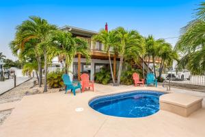 a house with a pool and chairs and palm trees at Dockside in Marathon