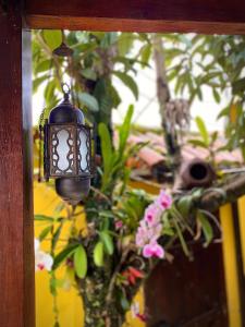 een zwart licht hangend aan een muur met planten bij MAI Chameguin Hospedagens Paraty in Paraty