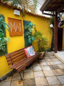 a bench sitting in front of a yellow wall at MAI Chameguin Hospedagens Paraty in Paraty