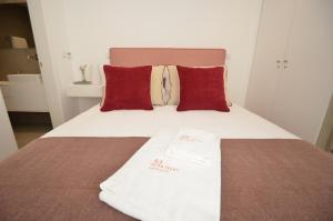 uma cama com almofadas vermelhas e uma toalha branca em Oliva Teles 53 Apartments em Arcozelo