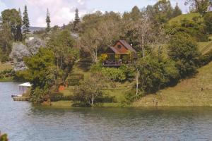 ein Haus auf einem Hügel neben einem See in der Unterkunft Cabaña Campestre en la represa del Peñol Guatape Antioquia in Guatapé