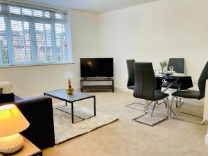 Modern 2 Bed Apt in Egham High Street, with private parking and Wifi في ايجهام: غرفة معيشة مع طاولة وكراسي وتلفزيون