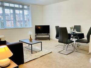 a living room with a table and chairs and a tv at Modern 2 Bed Apt in Egham High Street, with private parking and Wifi in Egham