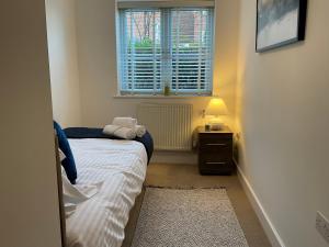 a small bedroom with a bed and a window at Modern 2 Bed Apt in Egham High Street, with private parking and Wifi in Egham
