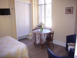 a room with a table with a vase of flowers on it at Chambres d'hôtes Résidence du Parc in Plombières-les-Bains