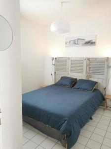 a bed with blue pillows in a white room at Villa Santoline, Saint-Denis-d'Oléron in Saint-Denis-dʼOléron