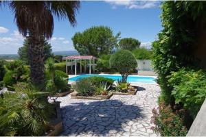 una piscina in un giardino con alberi e piante di Marie Jean Chambre d'hotes & Gite a Oupia