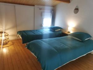 two beds in a room with blue sheets at Villa Santoline, Saint-Denis-d'Oléron in Saint-Denis-dʼOléron