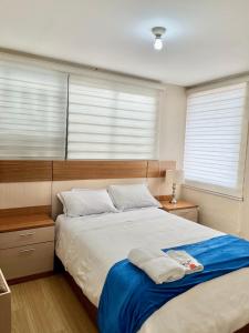 a bedroom with a large bed with two windows at VFC Suites Cuenca - Ecuador in Cuenca