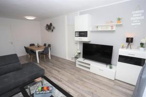 a living room with a couch and a tv and a table at Apartman Perla Deluxe in Poreč