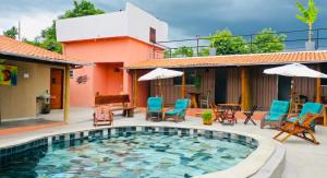 a pool with chairs and umbrellas next to a house at Pousada Yanah in Pirenópolis