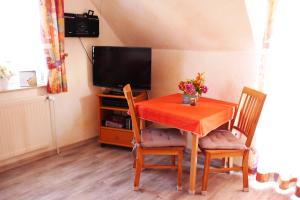 stół jadalny z 2 krzesłami i telewizor w obiekcie Haus Shalom w mieście Neuharlingersiel