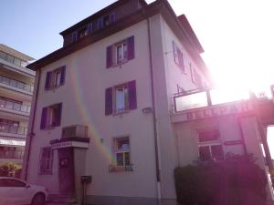 ein weißes Gebäude mit einem Regenbogen davor in der Unterkunft Bellpark Hostel in Luzern