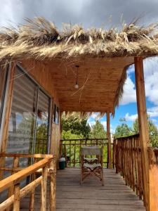 een houten terras met een rieten dak en een bank bij BluGlamp PlayaBlanca in Boyacá