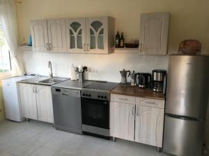 uma cozinha com armários brancos e um frigorífico de aço inoxidável em Villa Ida em Balatonmáriafürdő