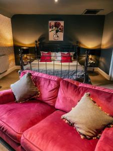 a red couch in a living room with a bed at The Stratford Park Hotel & Golf Club in Stratford-upon-Avon