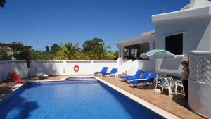 a woman standing next to a swimming pool next to a house at Villa El Alcazar in Carvoeiro