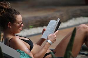 a woman sitting in a chair reading a book at Arenal Poshpacker in Fortuna