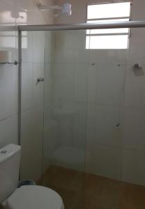a bathroom with a toilet and a glass shower at Pousada Vale da Serra in Serra Negra