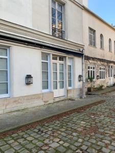 a building with a cobblestone street in front of it at Luxe Parisien - Petit Varenne in Paris