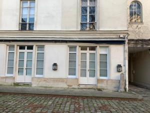 - un bâtiment blanc avec des fenêtres et une porte dans l'établissement Luxe Parisien - Petit Varenne, à Paris