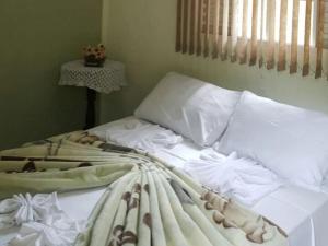 1 cama no hecha con sábanas y almohadas blancas en Pousada Vale da Serra, en Serra Negra