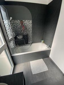 Ein Mann, der ein Bild von einer Badewanne im Badezimmer macht. in der Unterkunft Logement Confort 2 Chambres / Séjour-cuisine proche de Montpellier in Saint-Aunès + 33 Fotos