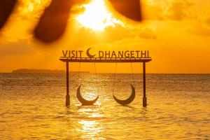 a sign in the middle of the ocean with two boats at Sunset Beach View in Dhangethi