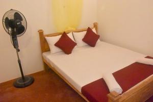 a bedroom with a bed with a fan next to it at Chipmunk Home Stay in Anuradhapura
